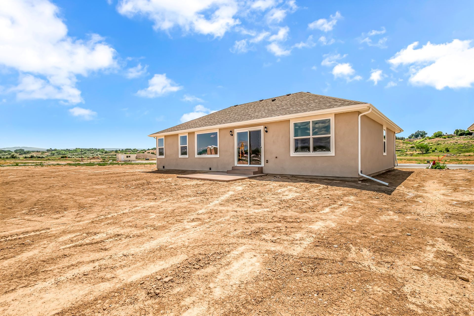 A house is sitting in the middle of a dirt field.