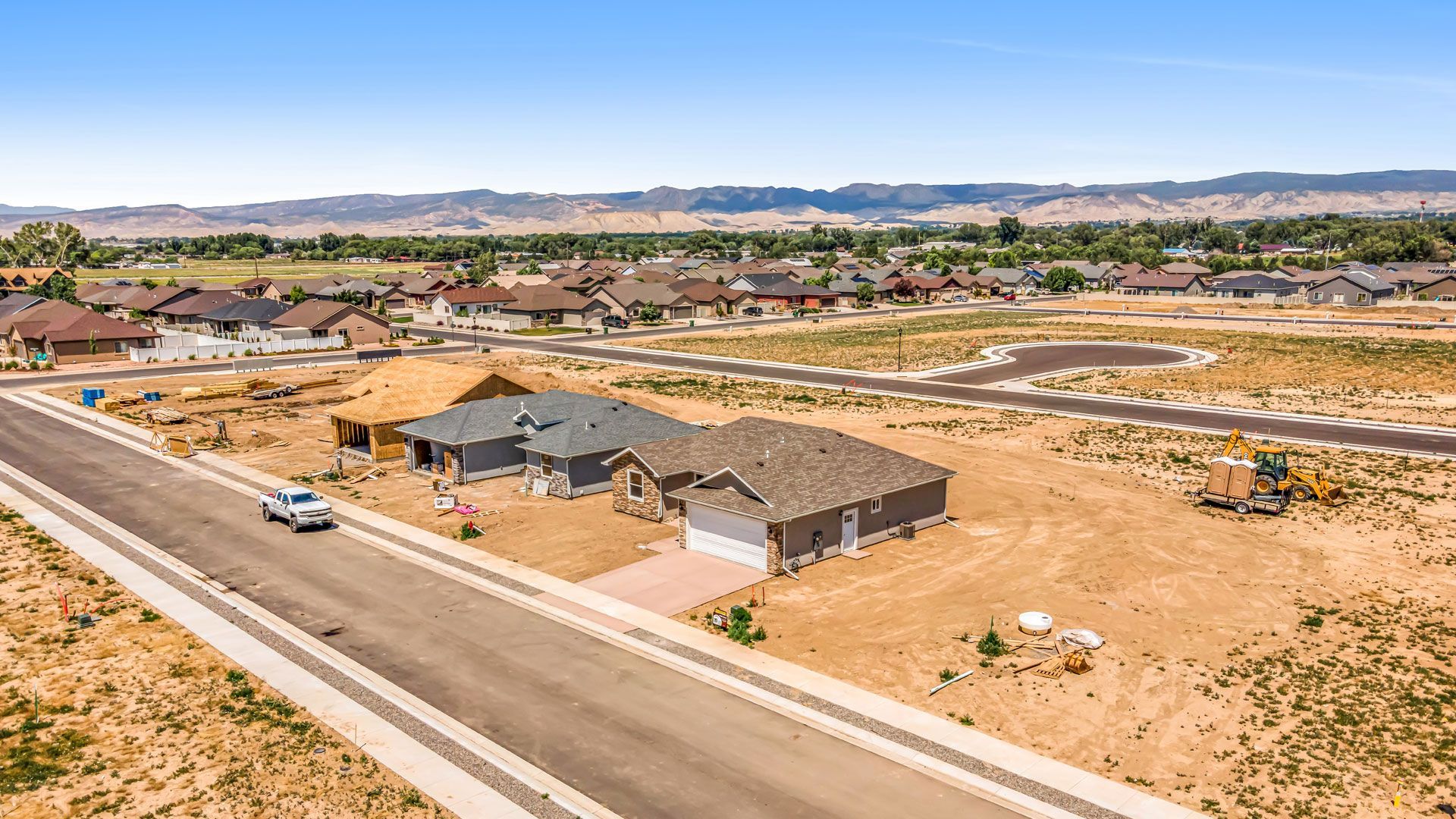 An aerial view of a residential area with houses and a truck driving down a road.