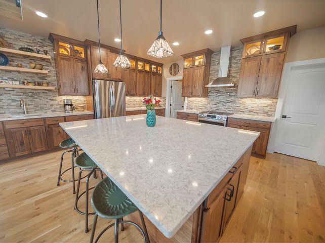 A kitchen with white cabinets , stainless steel appliances , and a large island.