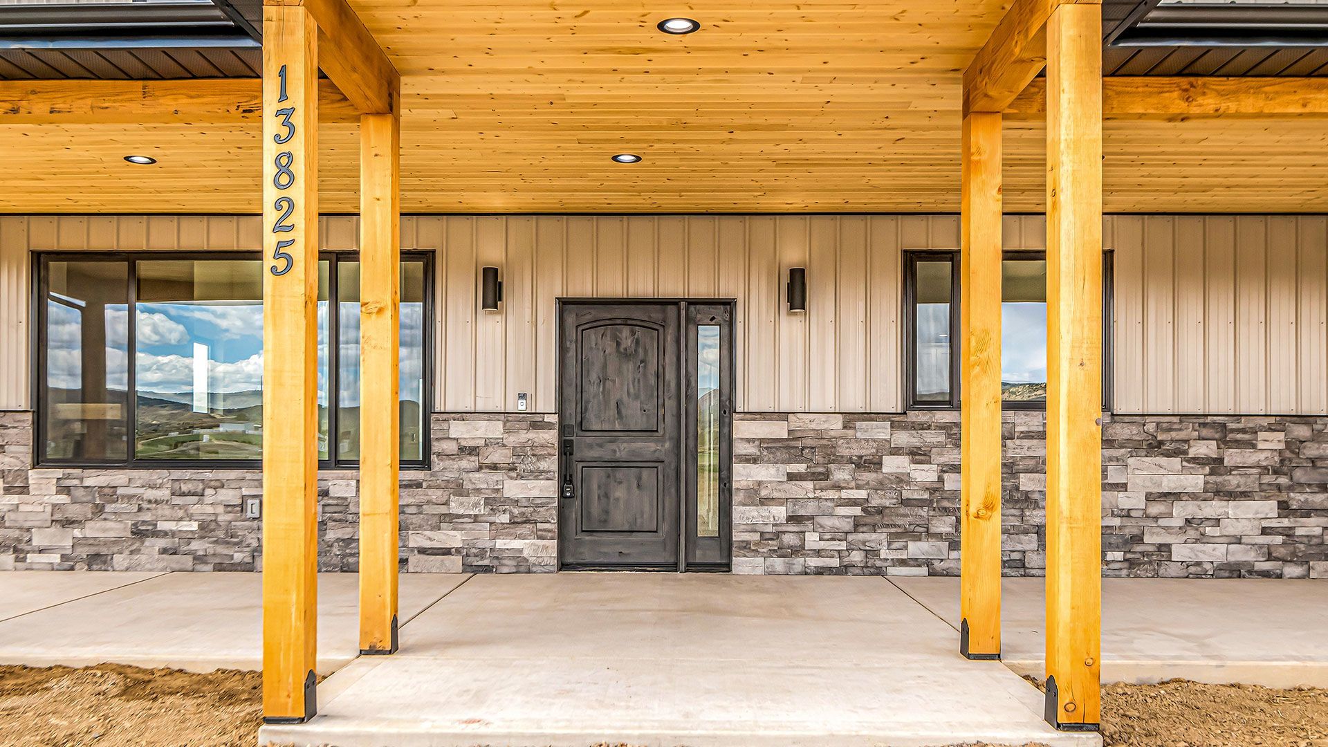 The front door of a house with a wooden porch and a stone wall.