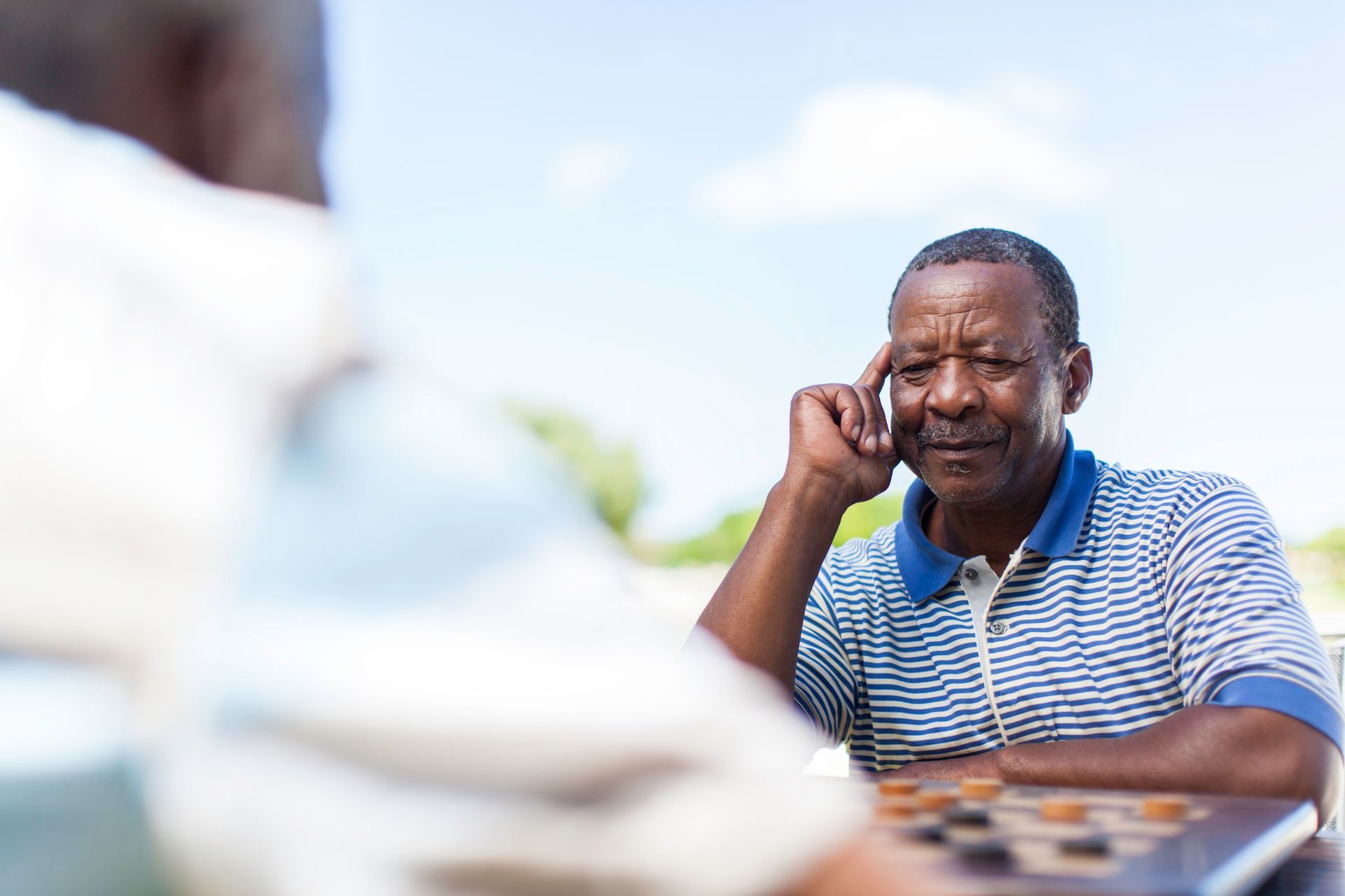Two men are sitting at a table playing a game of checkers.