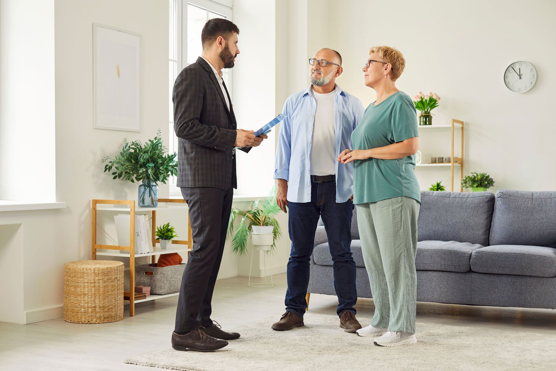 Real estate agent hands keys to a couple in a bright living room.