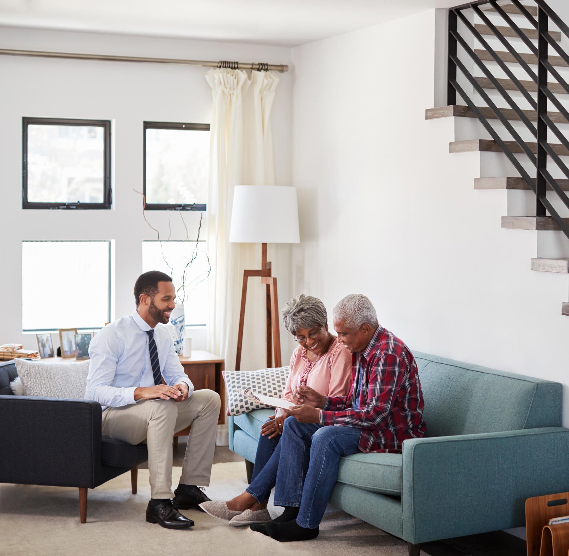 Financial advisor with clients looking at paperwork on a couch in a living room.