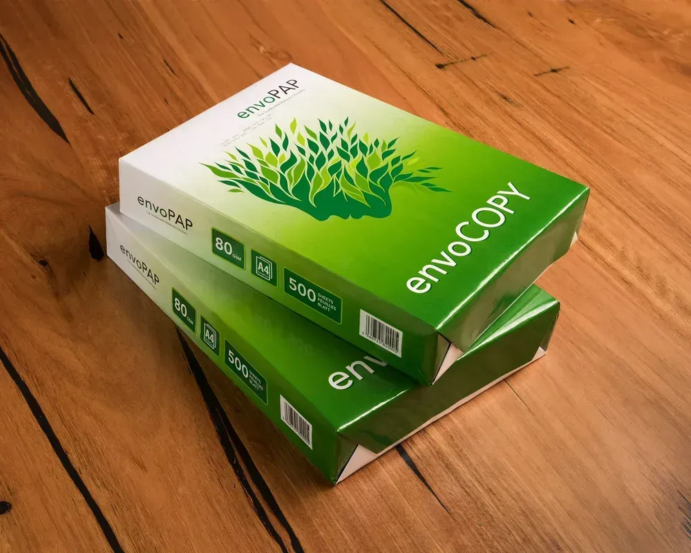Two stacks of EnvoCopy paper boxes on a wooden surface. Boxes are green and white with a leaf design.