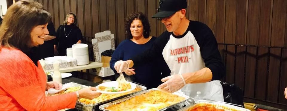 People serving food at an event. A man in a 