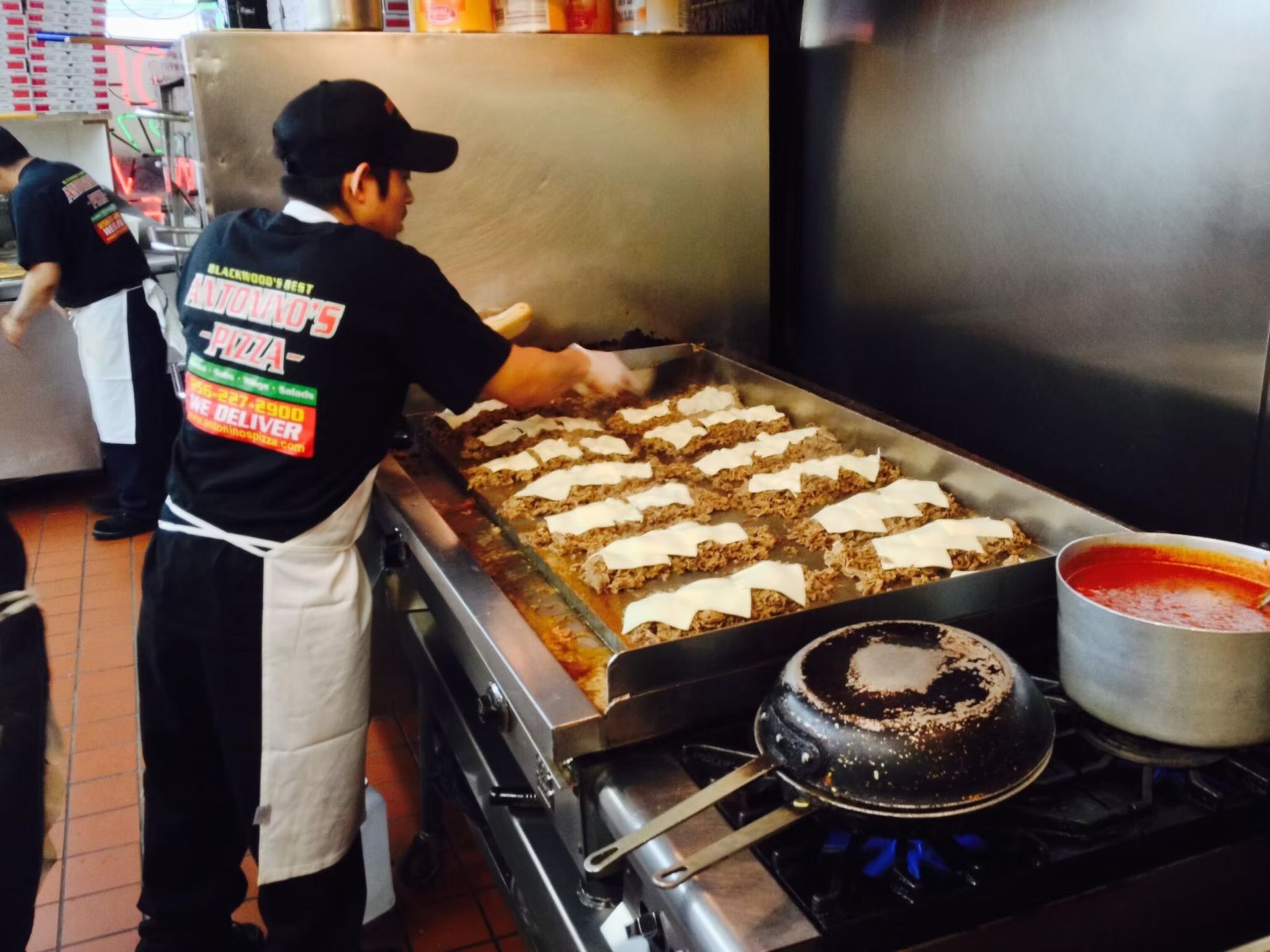 Cook grilling food on a large flattop griddle. Restaurant kitchen.