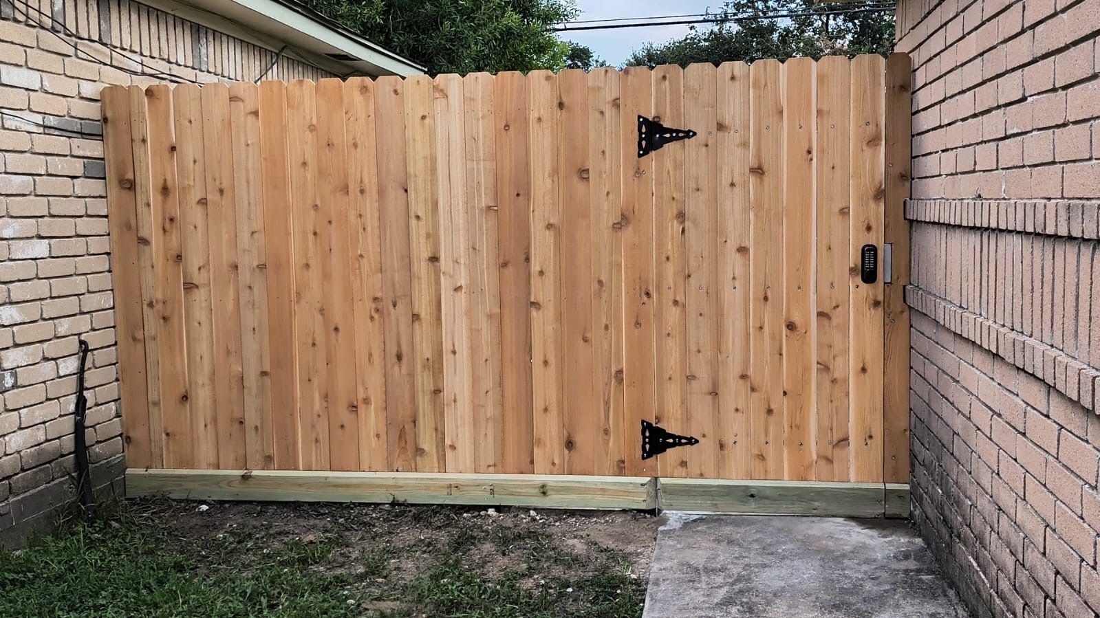 A wooden fence is sitting next to a brick wall.