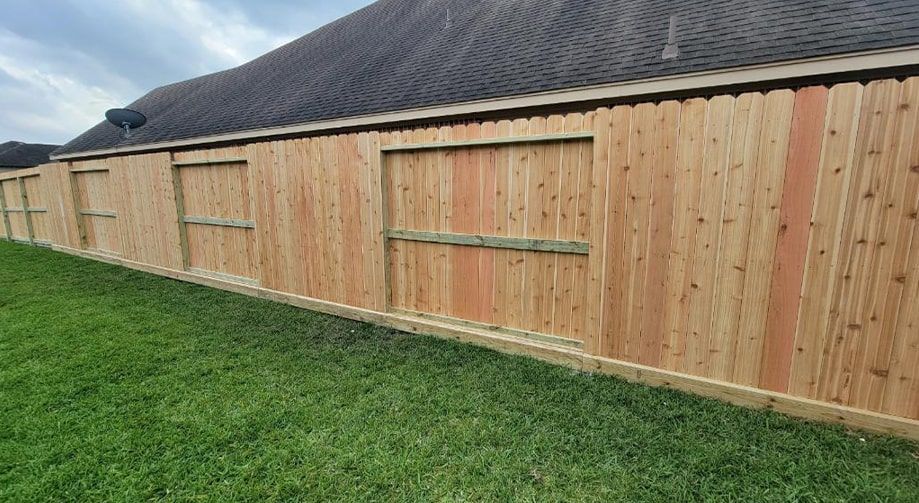 A wooden fence is in the backyard of a house.