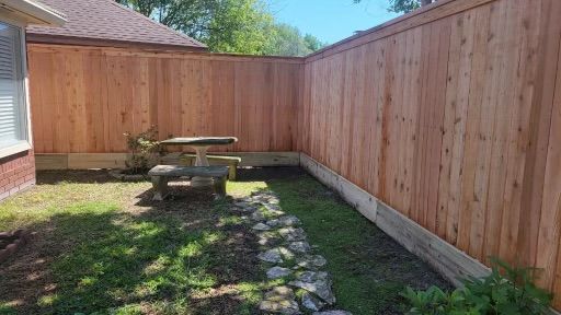 A wooden fence with a picnic table in the backyard of a house.