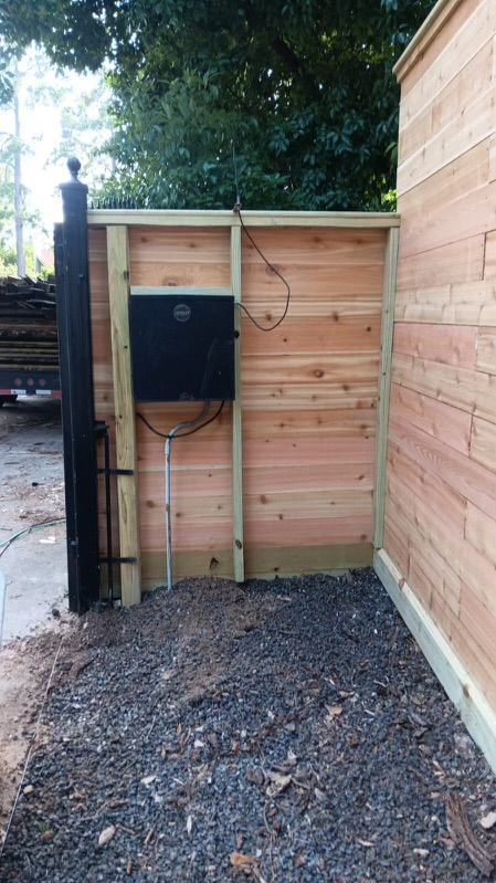 A wooden fence with a black box attached to it.