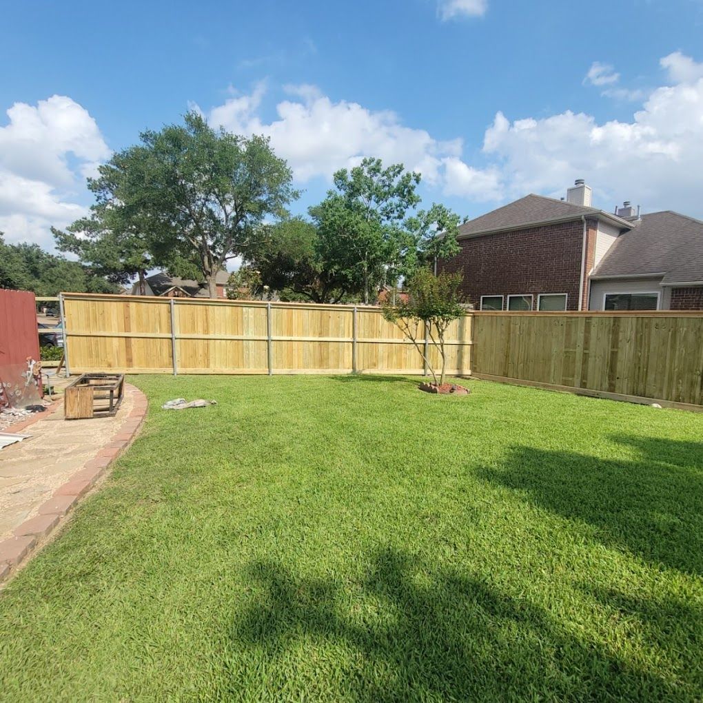 A backyard with a wooden fence and a lush green lawn.
