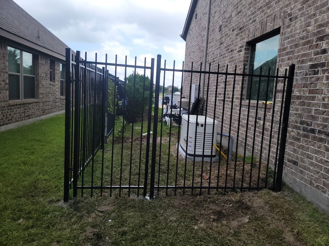 A black metal fence is in front of a brick building.