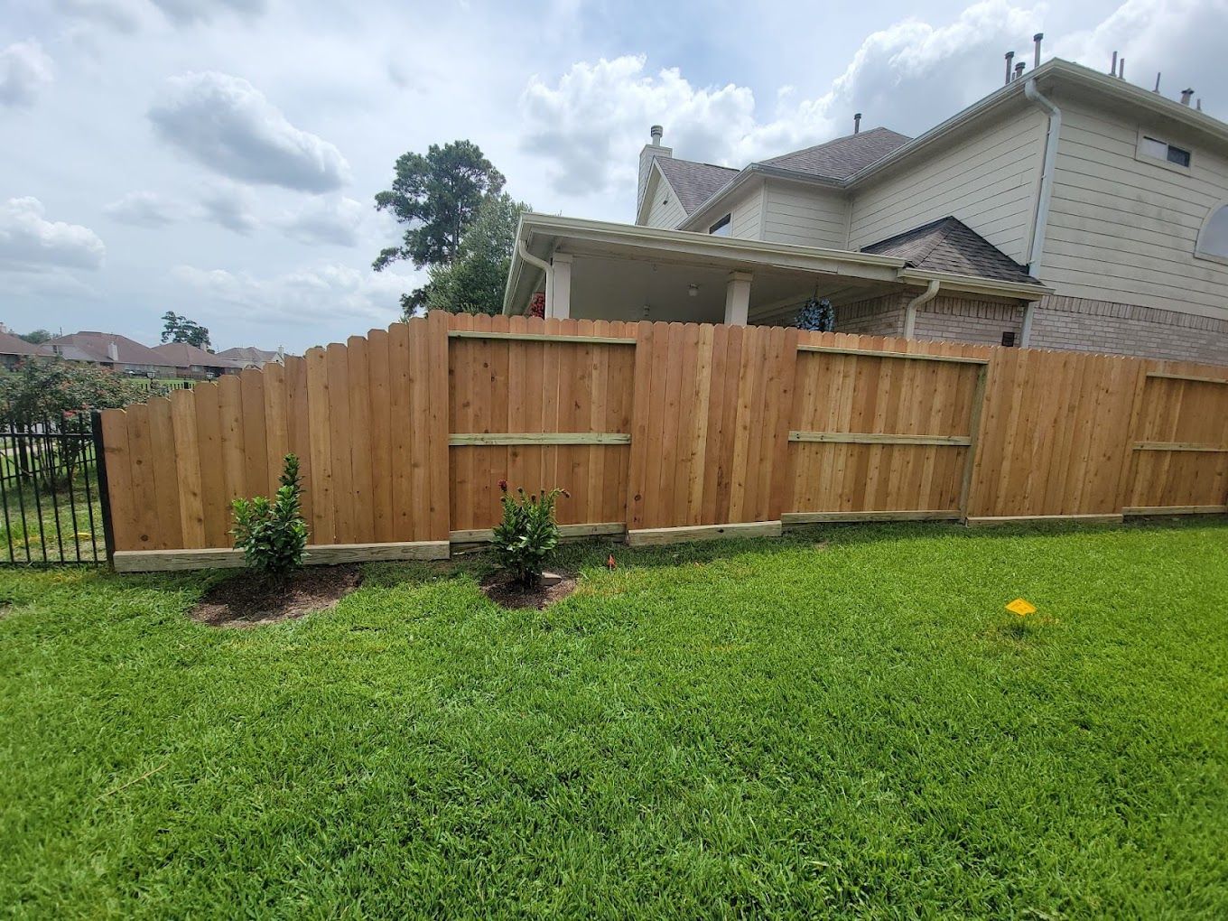 A wooden fence is in the backyard of a house.