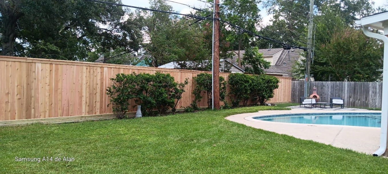 A wooden fence surrounds a swimming pool in a backyard.