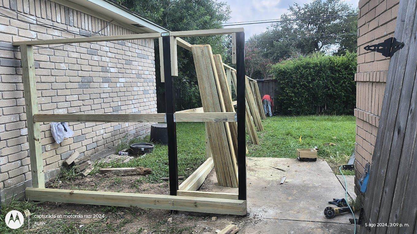 A wooden fence is being built in the backyard of a house.