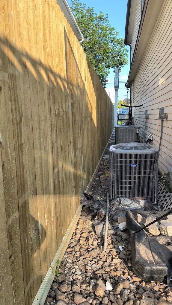 A wooden fence along the side of a house with an air conditioner.