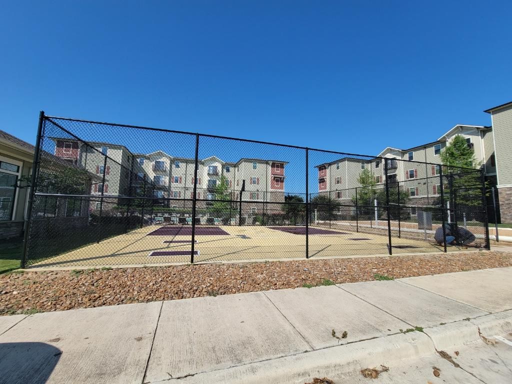 A basketball court with a chain link fence in front of a building.