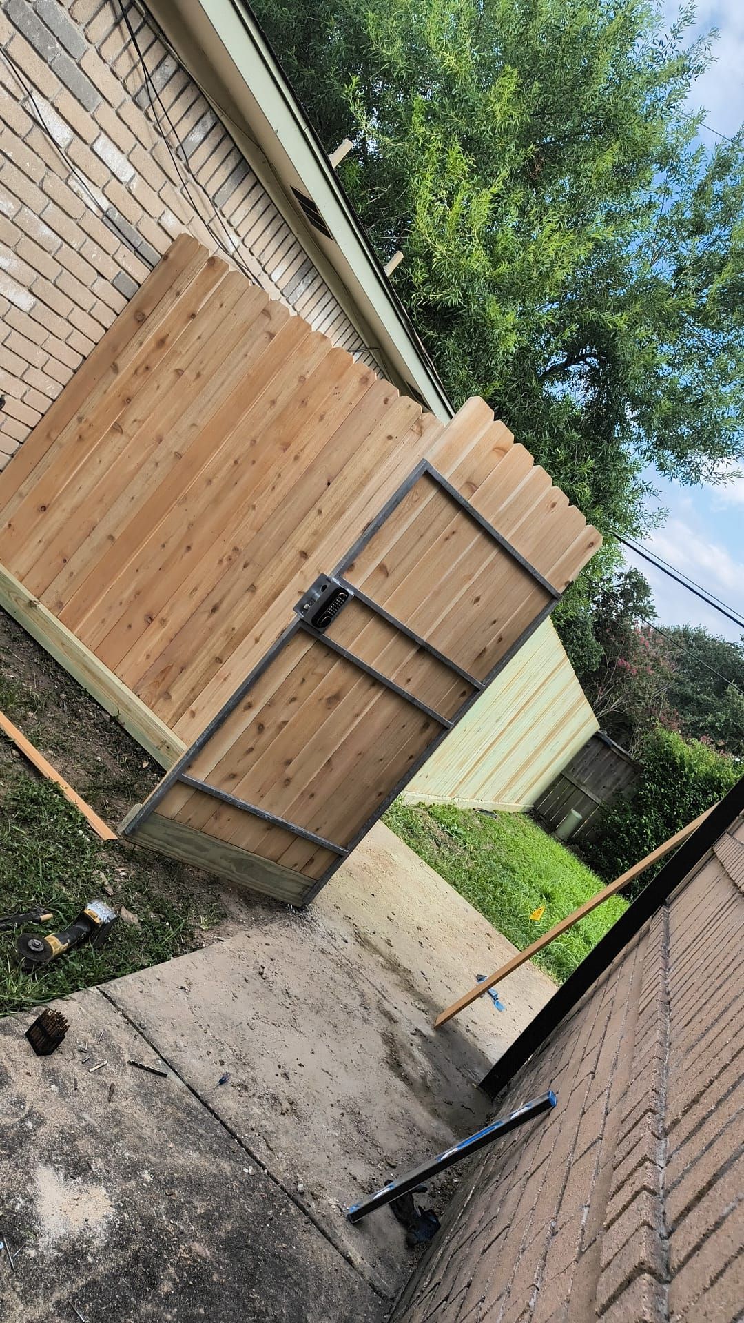 A wooden fence is being built in the backyard of a house.