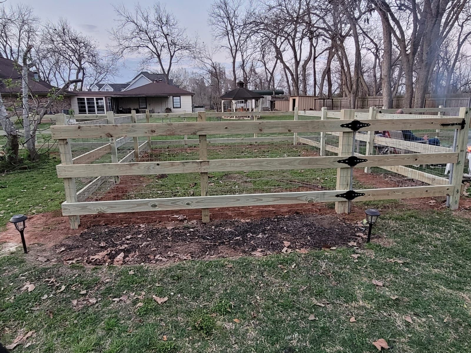 A wooden fence is sitting in the middle of a grassy field.