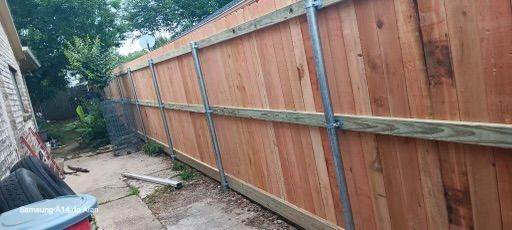 A wooden fence is being built in the backyard of a house.