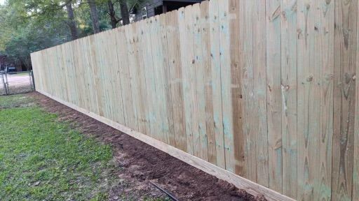 A wooden fence is sitting in the middle of a lush green field.