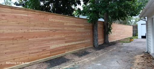A wooden fence is being built in the backyard of a house.