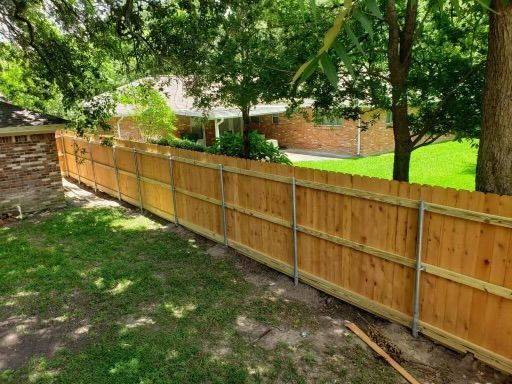A wooden fence is being built in the backyard of a house.