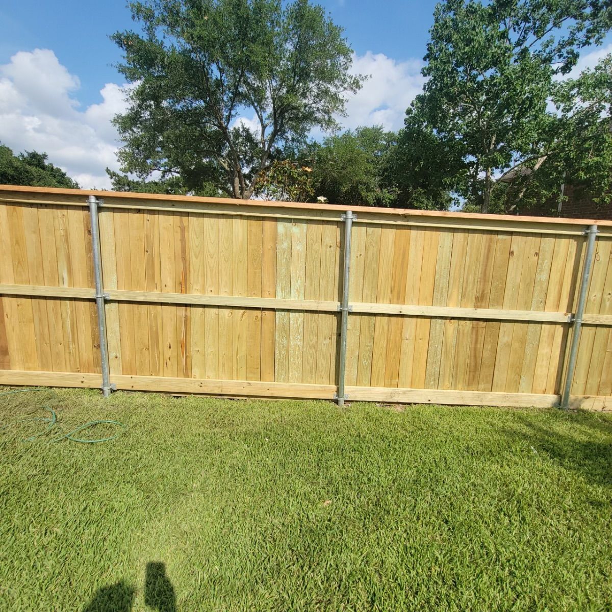 A wooden fence is sitting in the middle of a lush green field.