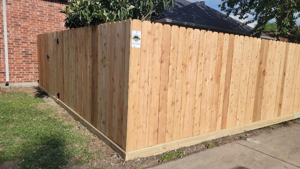 A wooden fence is sitting in front of a brick house.