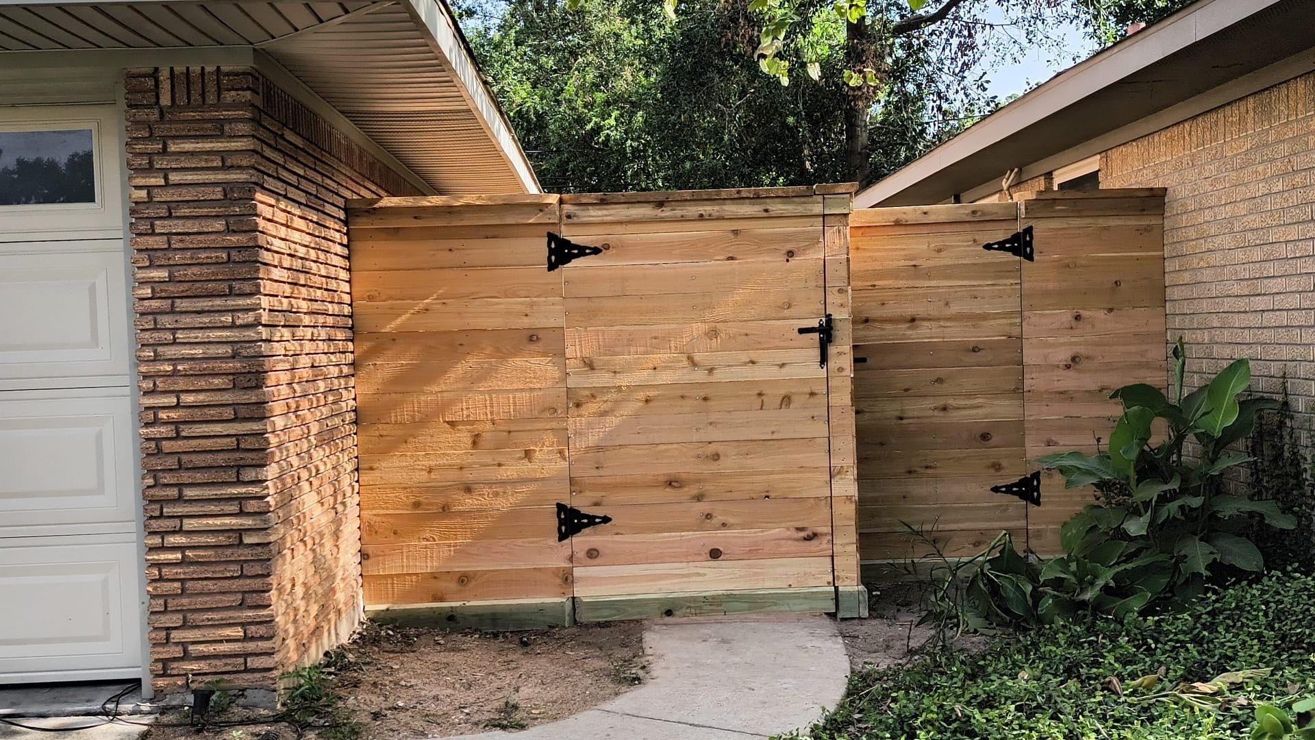 A wooden fence is in front of a brick house.