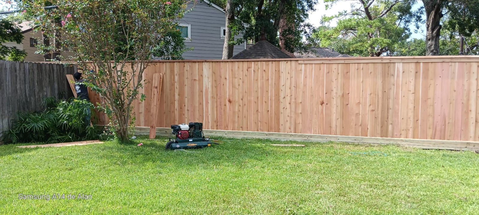 A wooden fence is sitting in the middle of a lush green yard.