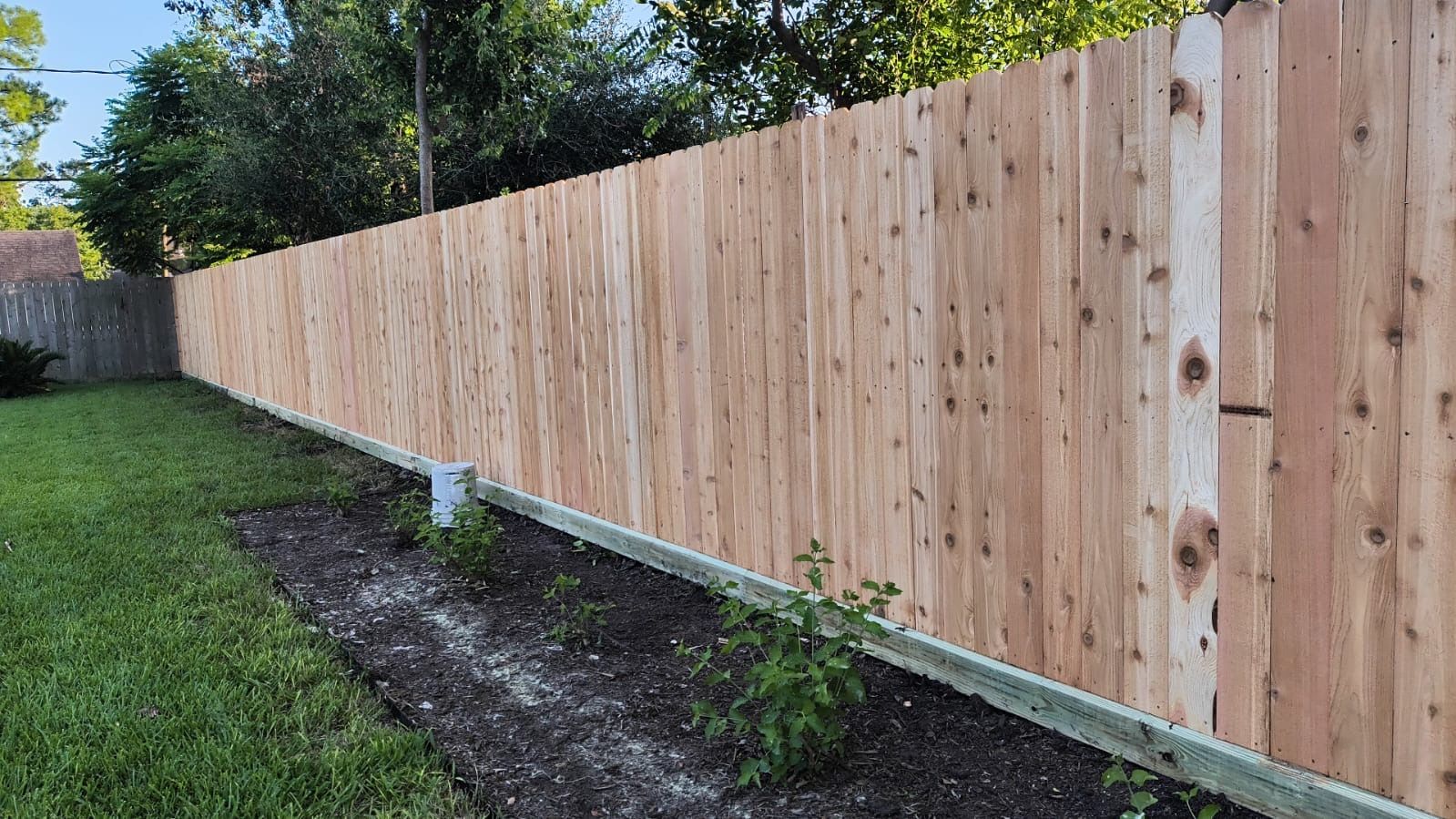 A wooden fence is sitting on top of a lush green lawn.