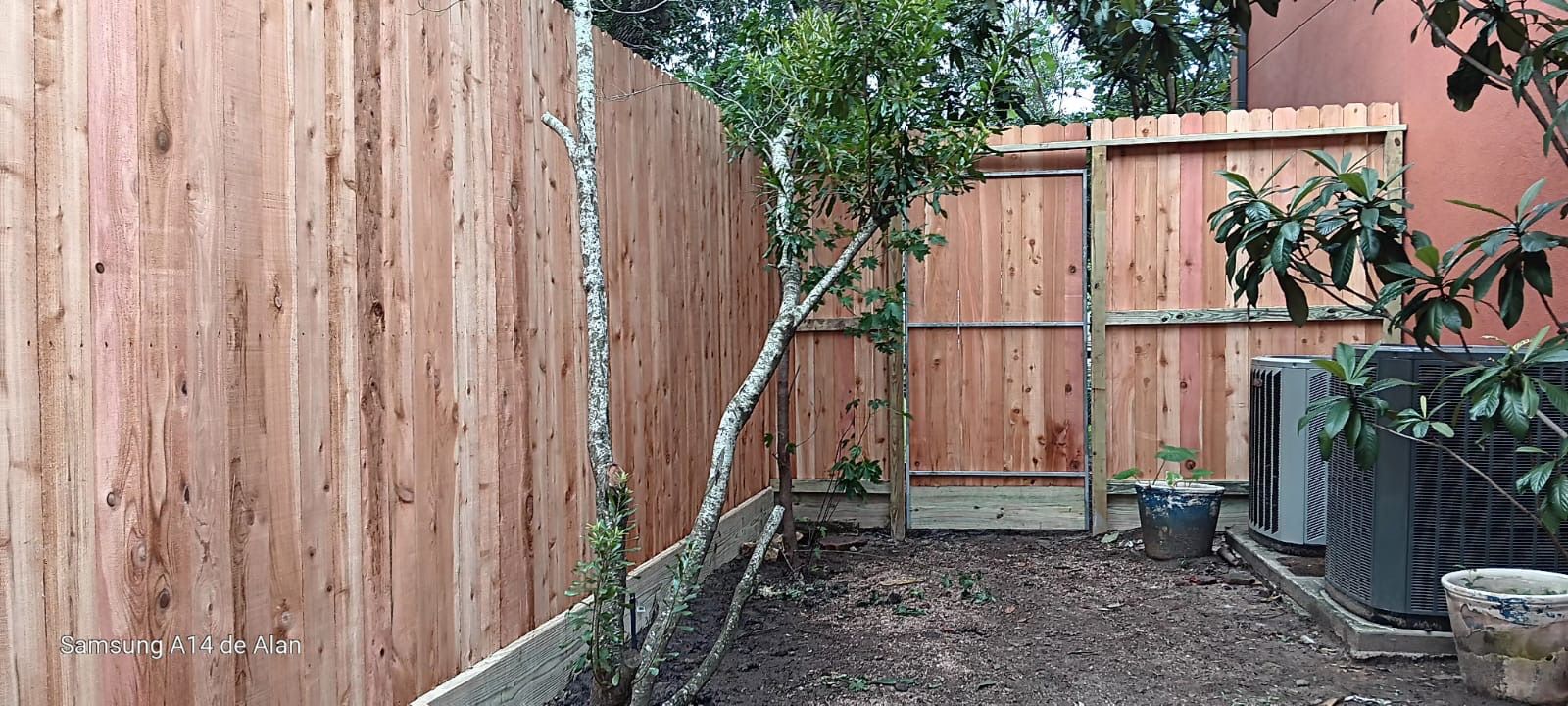 A wooden fence is in the backyard of a house.