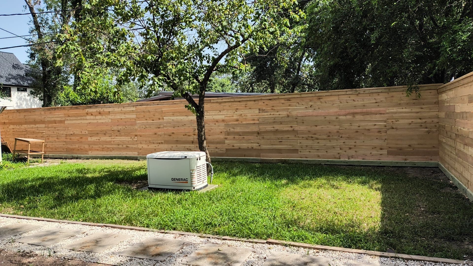 A wooden fence surrounds a lush green yard.