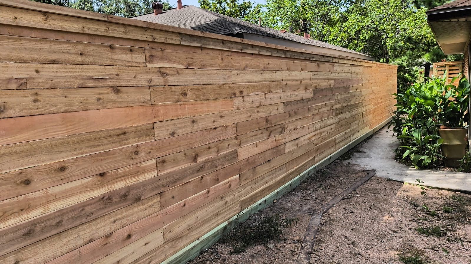 A wooden fence is sitting in the backyard of a house.