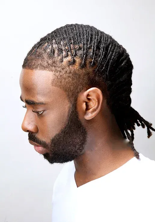 A man with dreadlocks and a beard is wearing a white shirt.