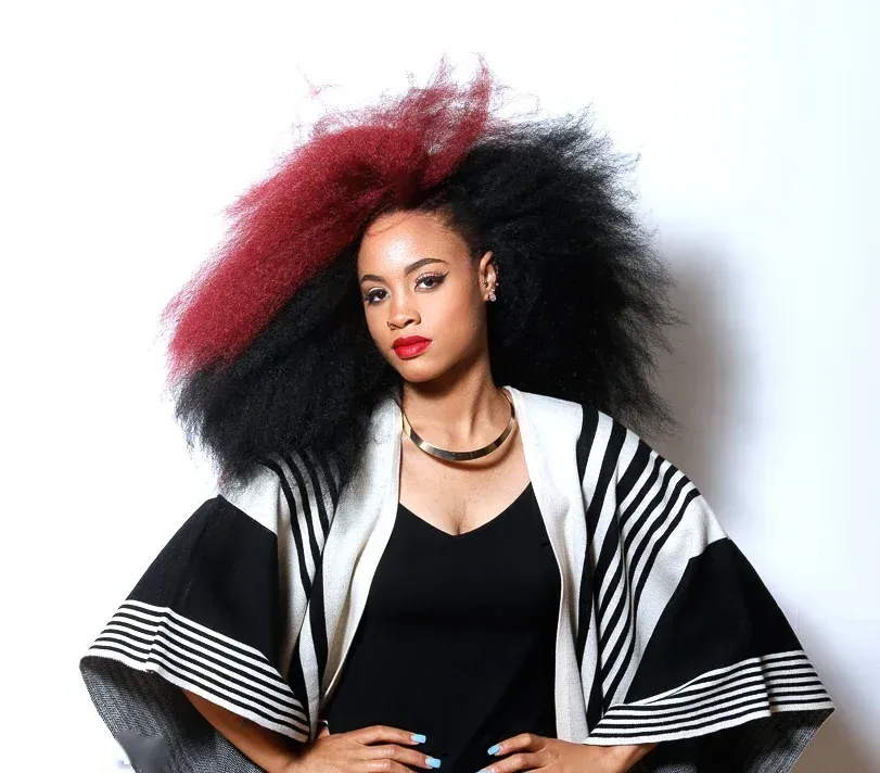 A woman with red and black hair is wearing a black and white poncho