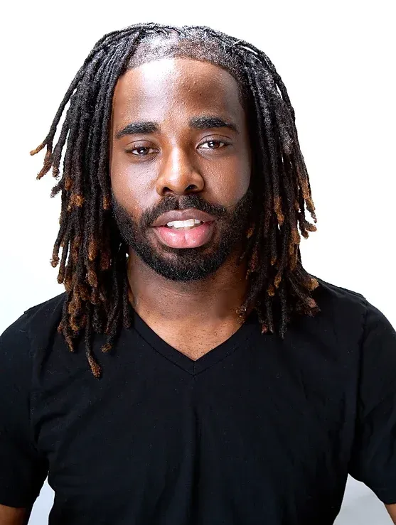 A man with dreadlocks and a beard is wearing a black shirt