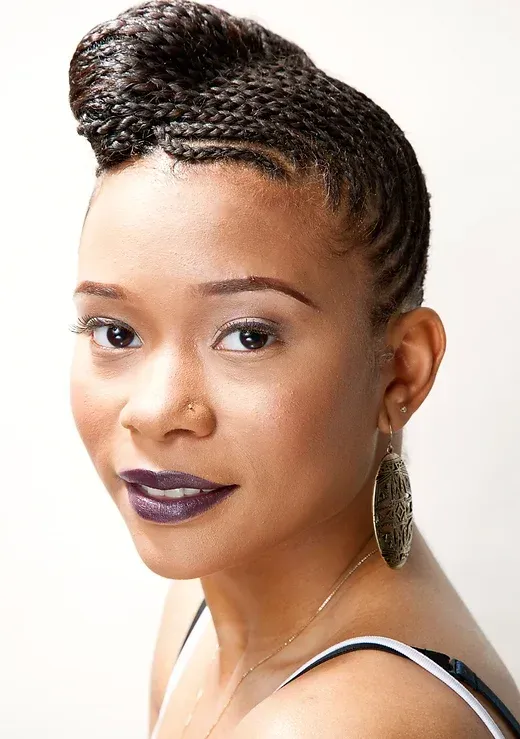 A close up of a woman 's face with braids and earrings