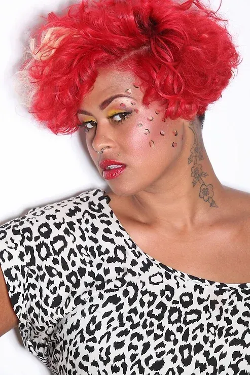 A woman with red hair is wearing a leopard print shirt