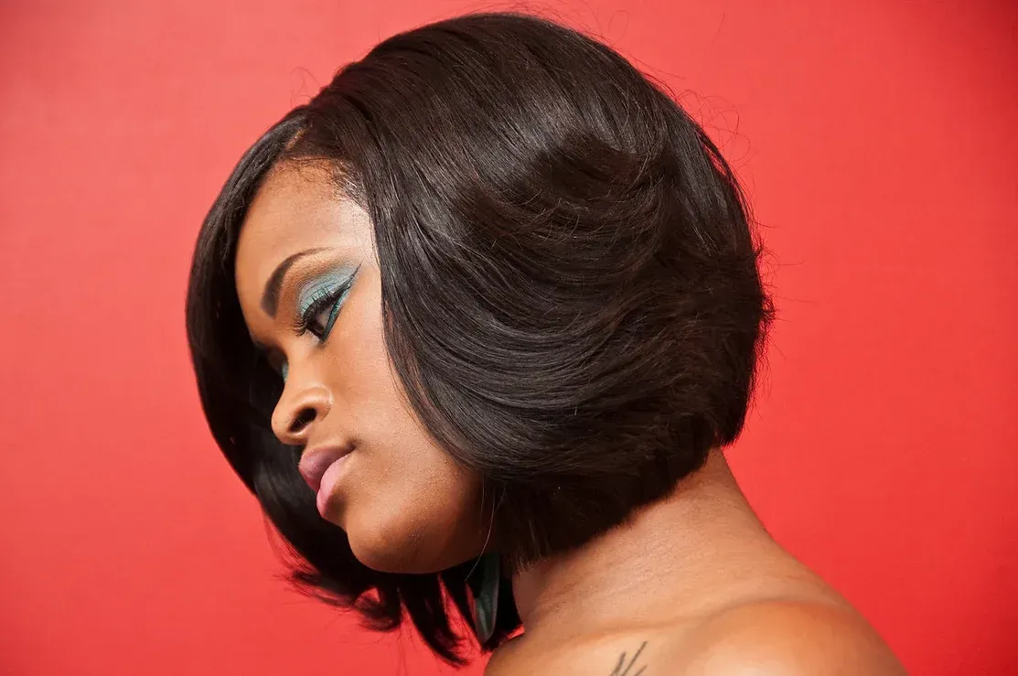 The woman is wearing a bob hairstyle and has a tattoo on her arm.