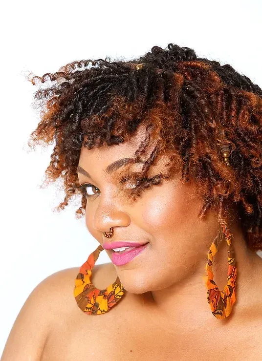 A woman with dreadlocks is wearing a pair of hoop earrings.