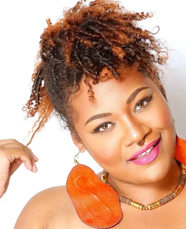 A woman with dreadlocks is wearing a necklace and earrings