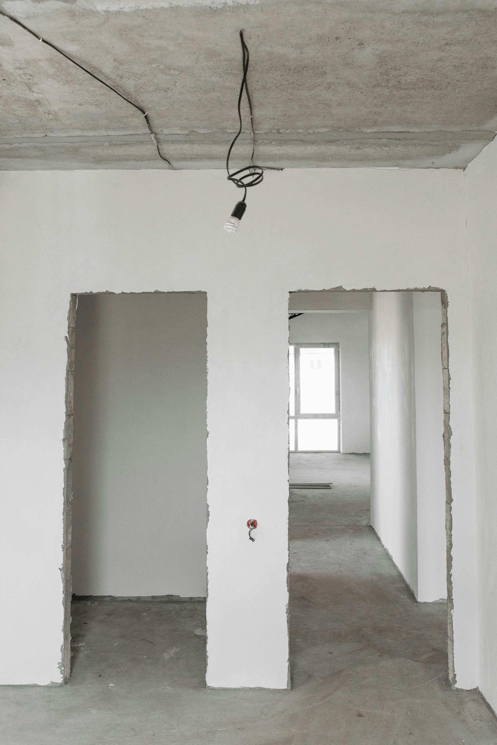 Empty room under construction with exposed concrete ceiling and unfinished doorways.