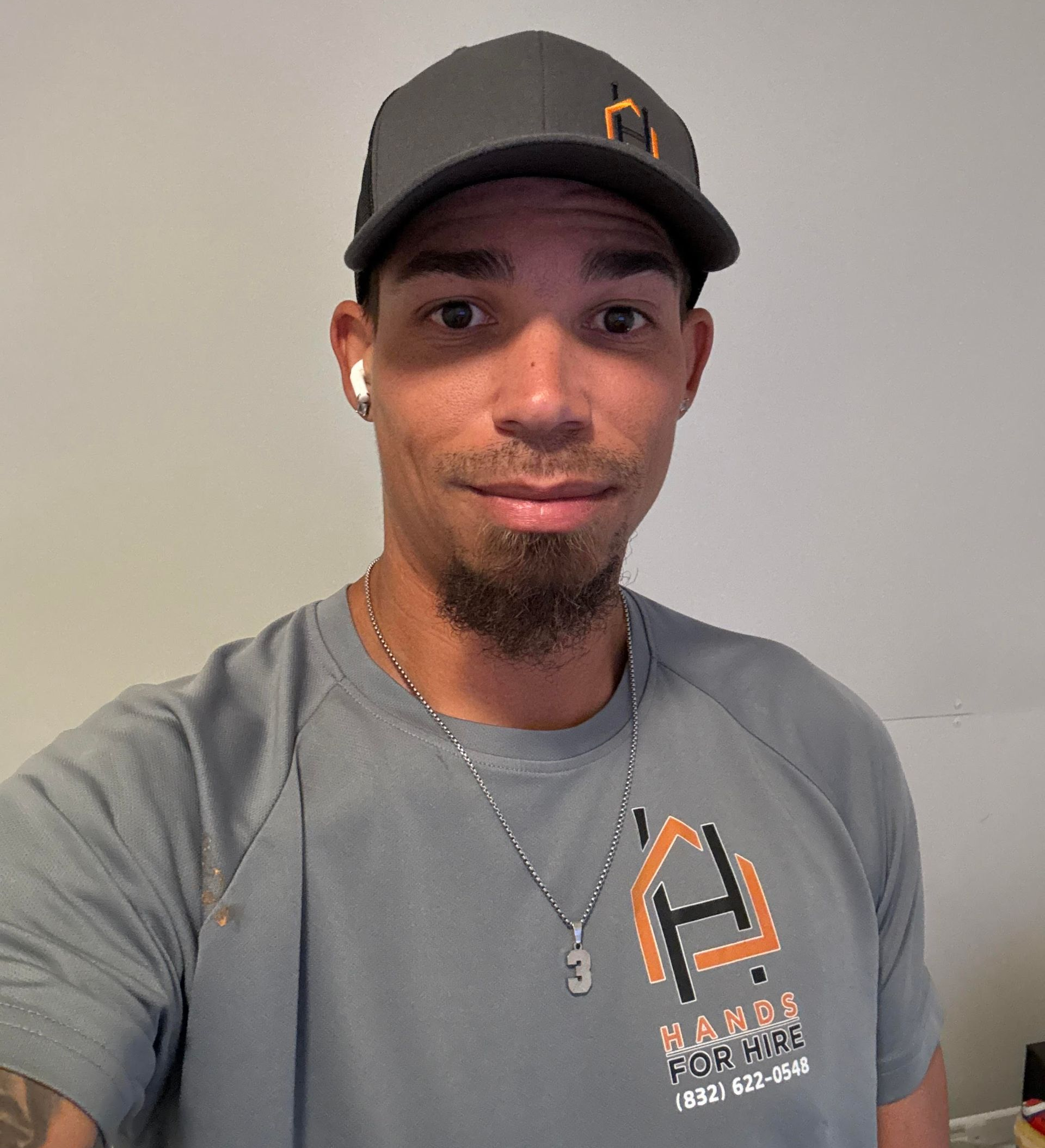 Man wearing a cap and shirt with a logo, smiling slightly.