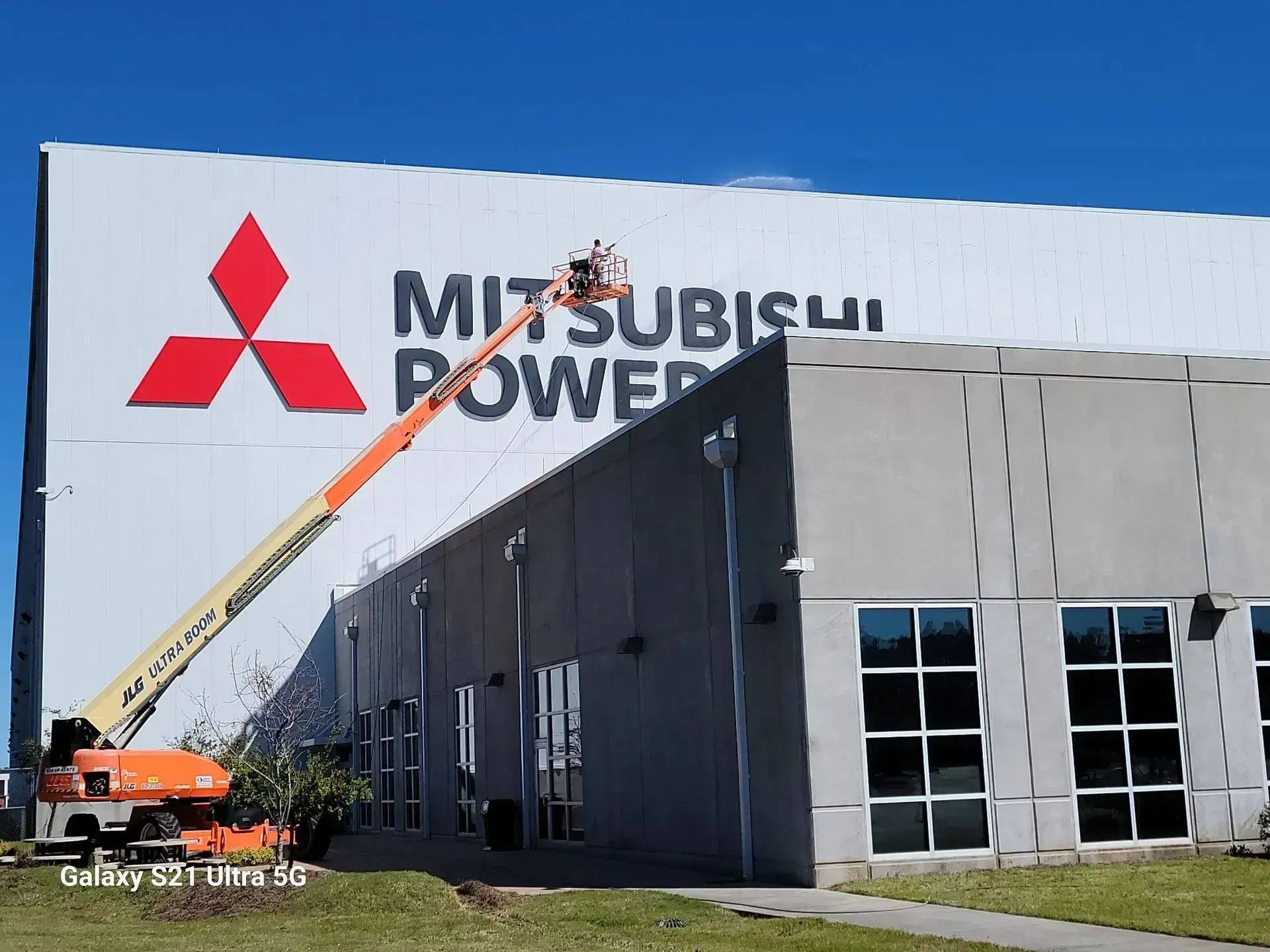 Mitsubishi Power building with a person in a lift working on the sign.