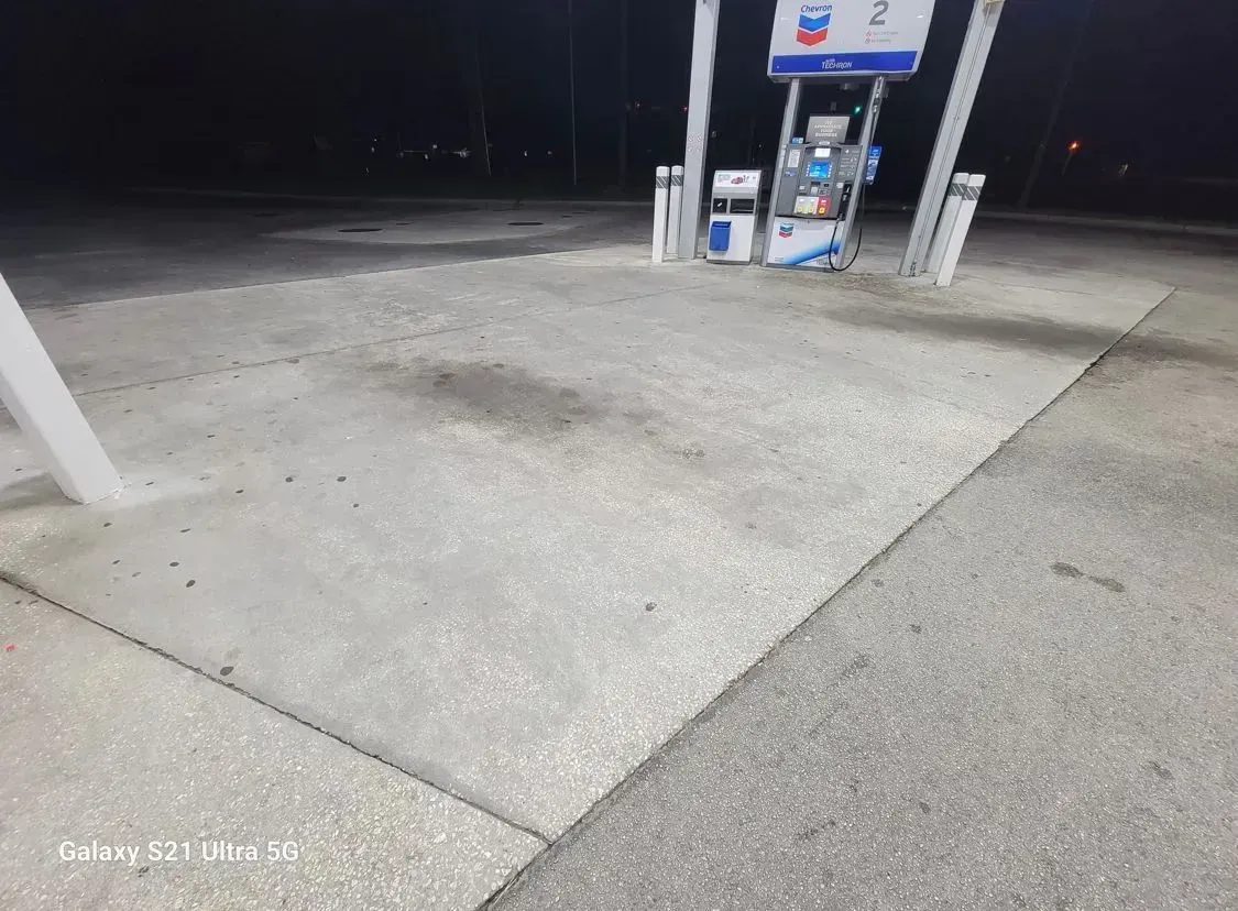 Concrete gas station, Chevron, at night. Gas pumps are visible.