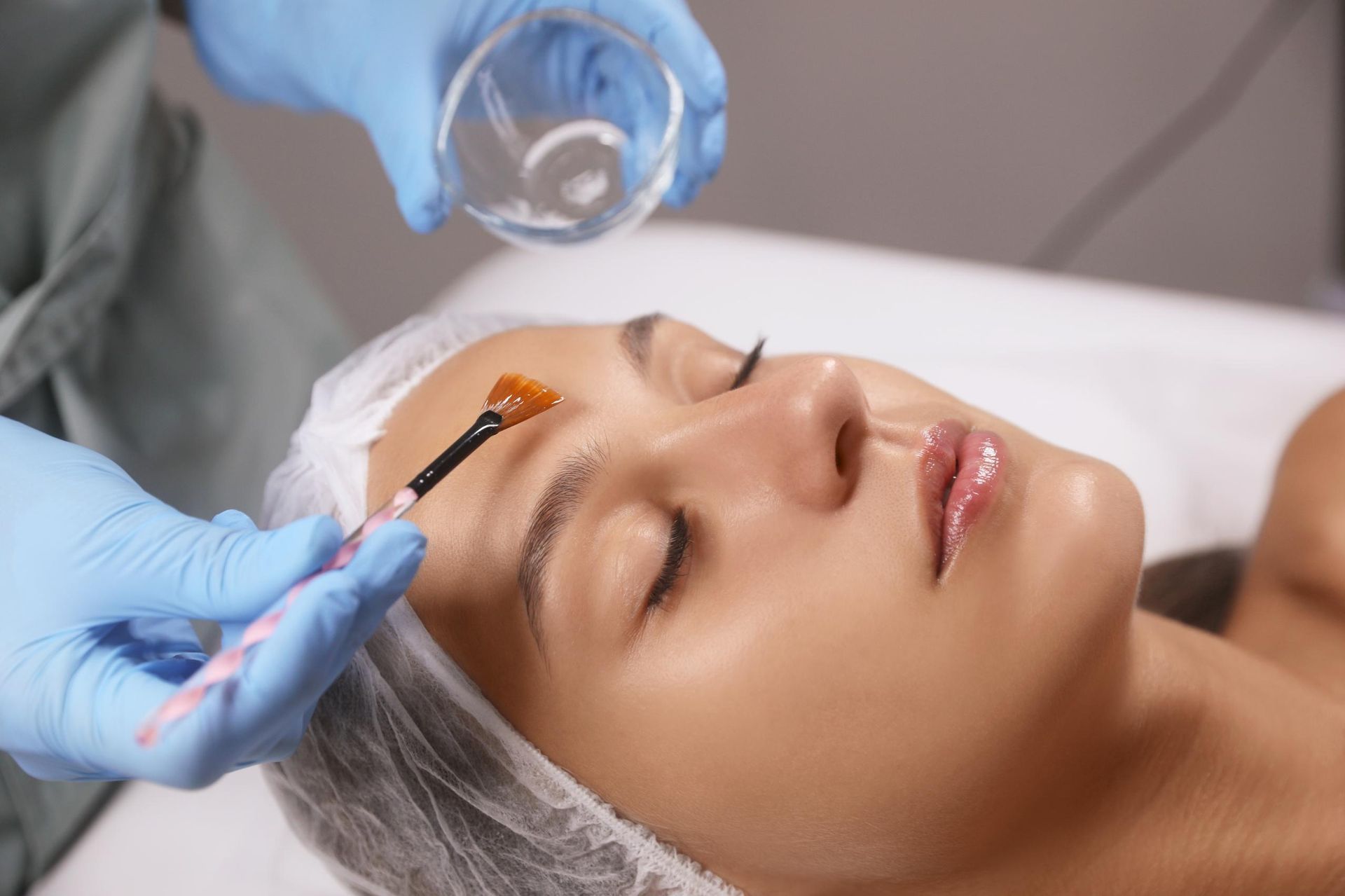 Cosmetic treatment applying serum to a relaxed face with a brush and dropper