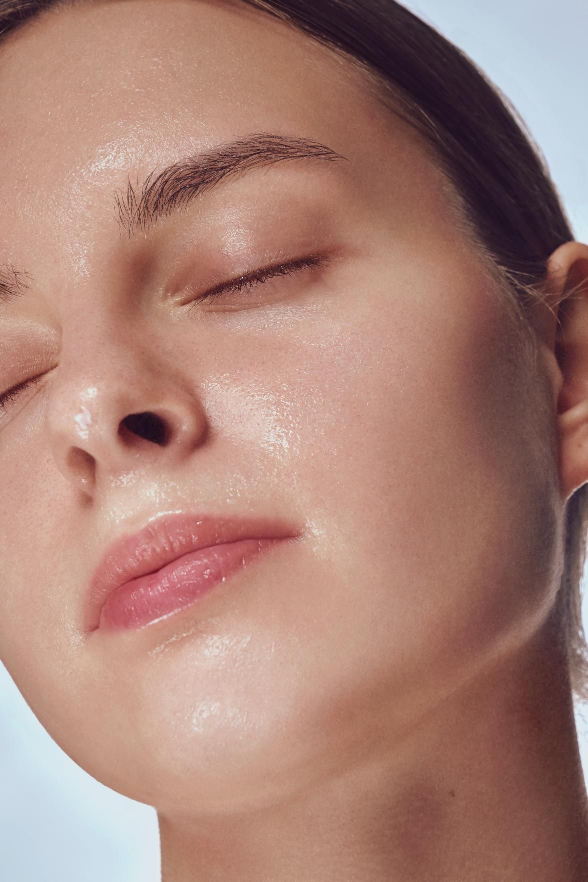 Close-up of a woman’s face with eyes closed, showing dewy skin and soft makeup