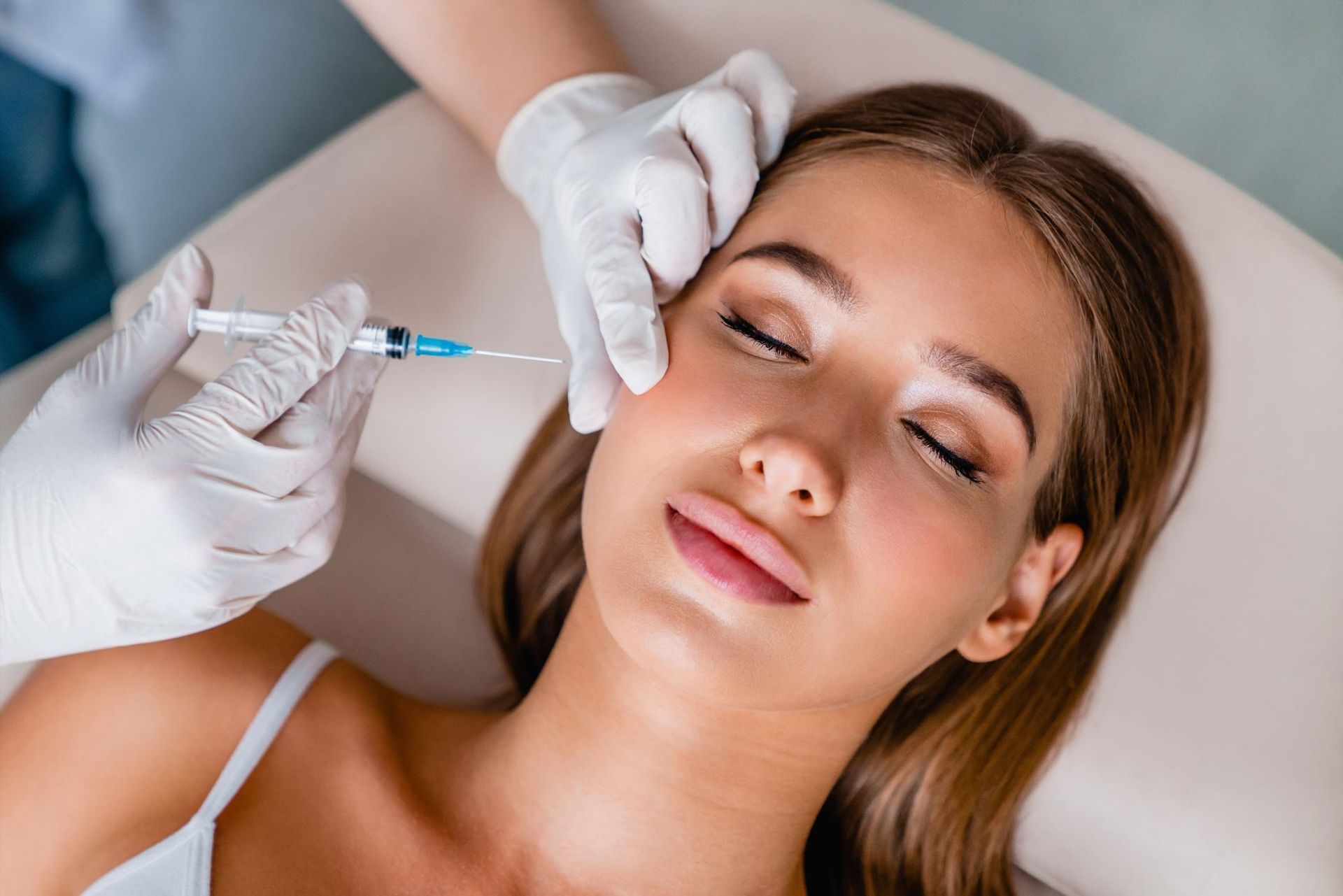 Gloved hands administering a facial injection to a relaxed woman in a spa setting